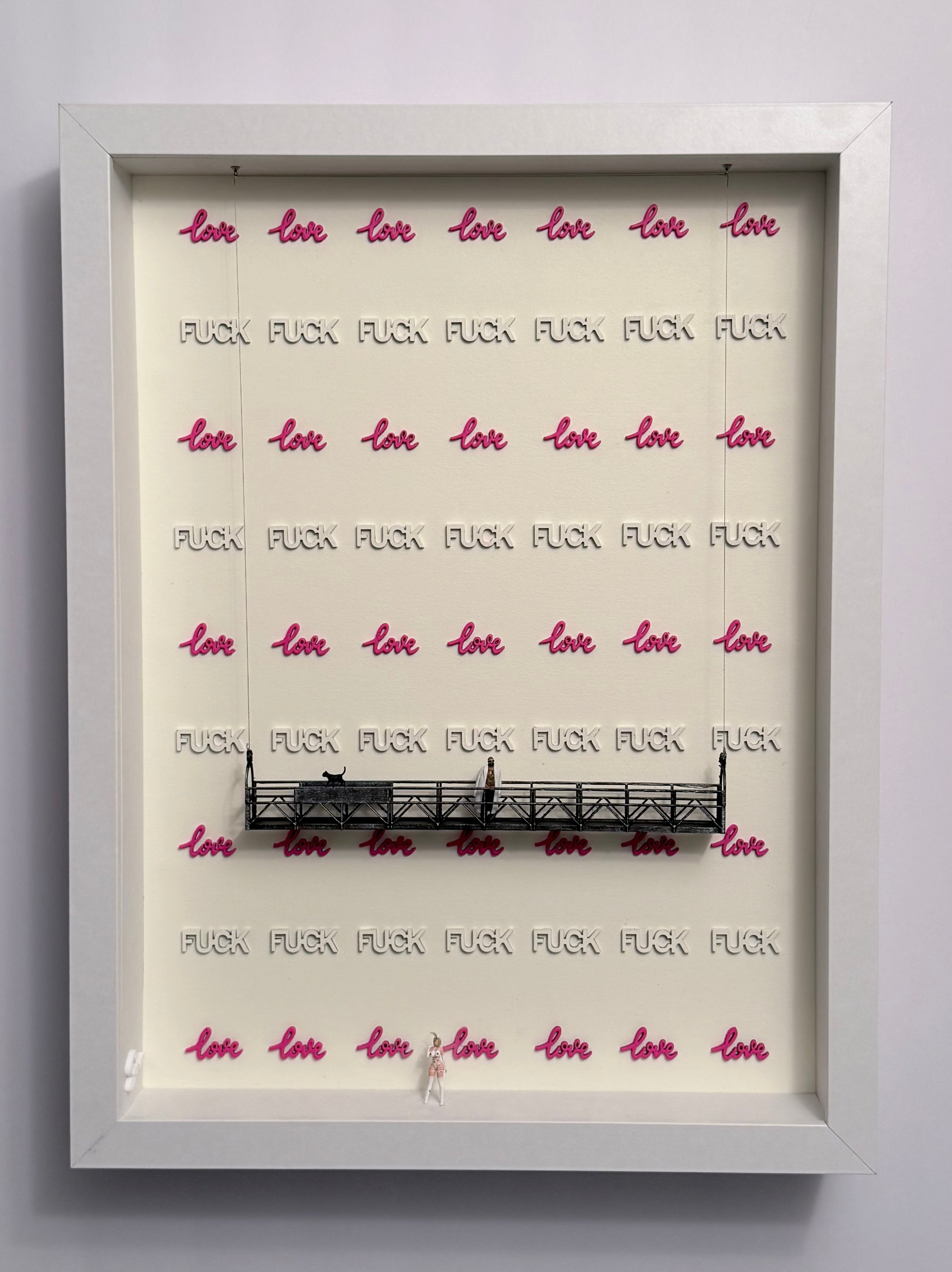 Shadow box artwork with the words FUCK and LOVE organized by line. A platform with a cat and a miniature figurine. Another miniature figurine is at the bottom.