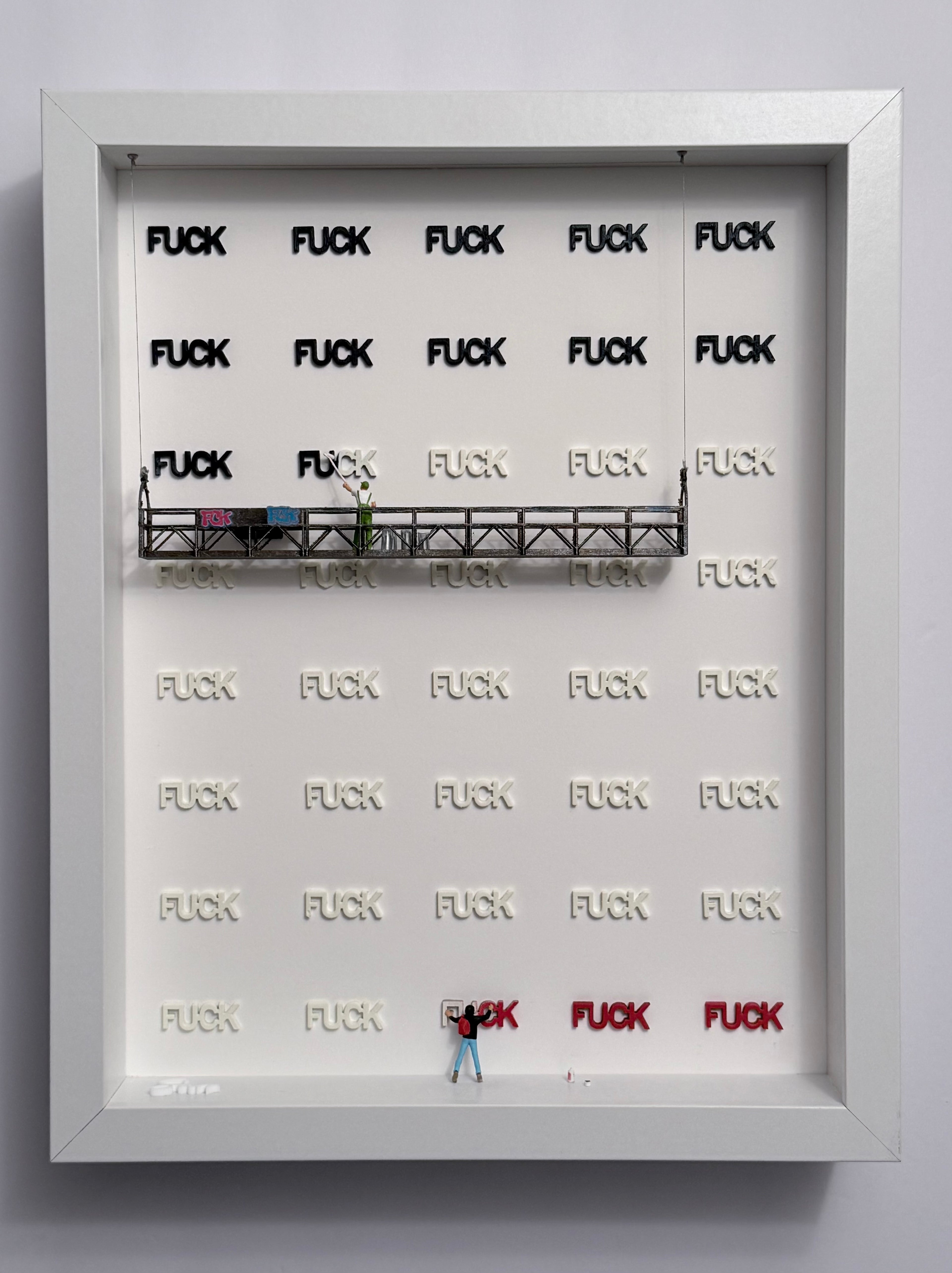 shadow box artwork with 'FUCK' in white, blue and red and a miniature figurines on a platform.