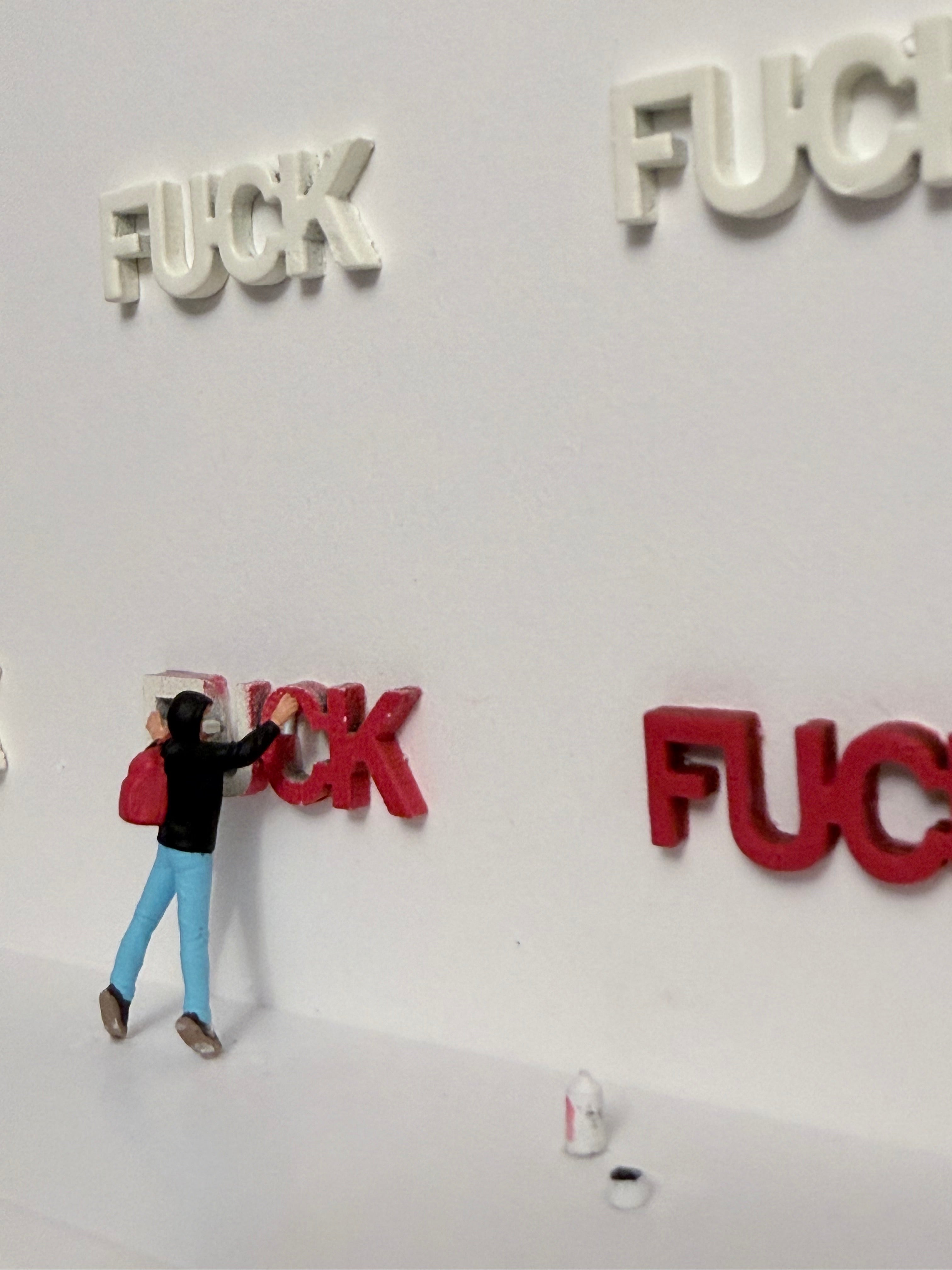 Miniature figurine standing next to large red letters spelling 'FUCK' on a white background