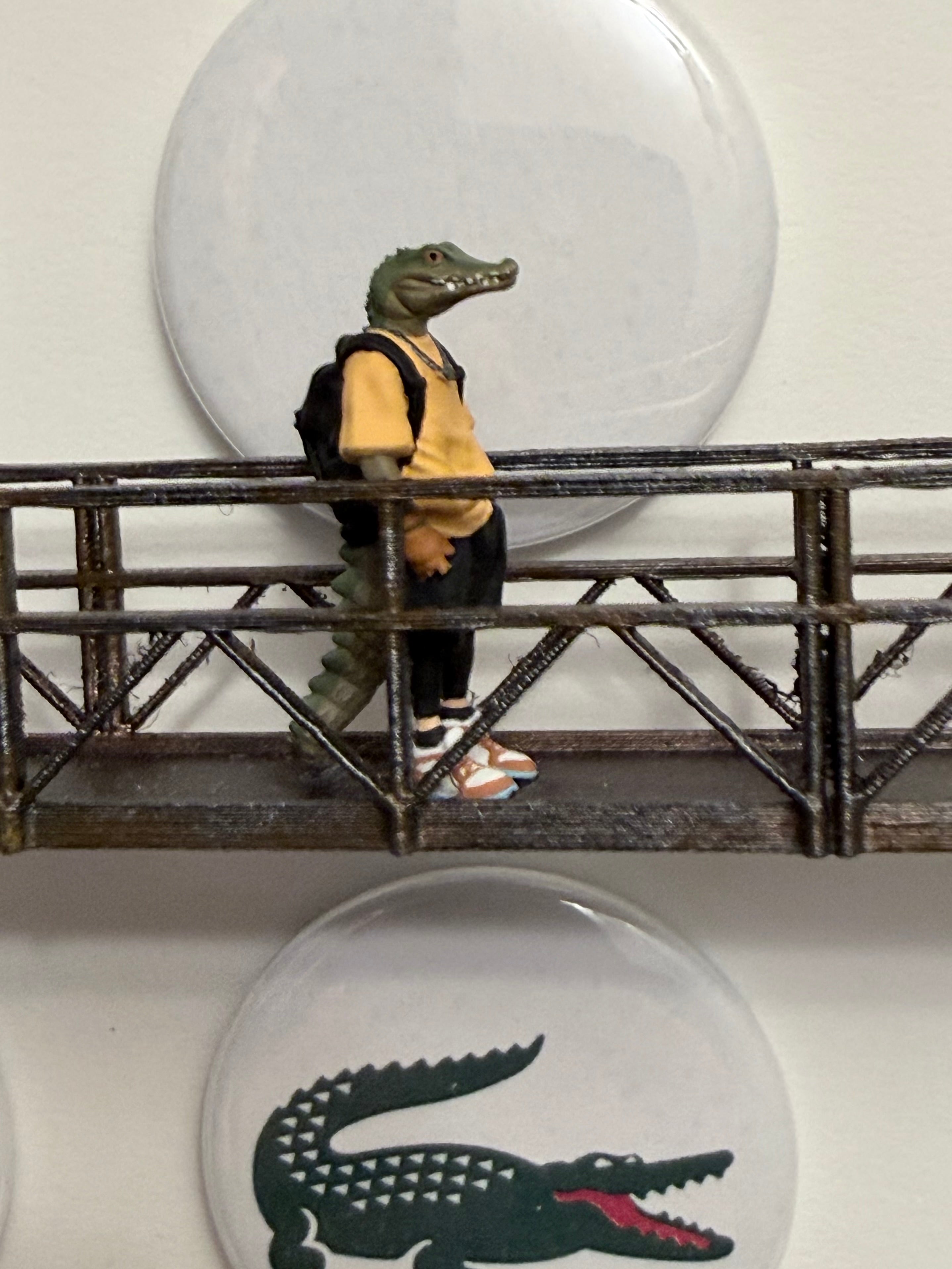 Miniature figurine of an alligator head on a platform with Lacoste logo in the background.