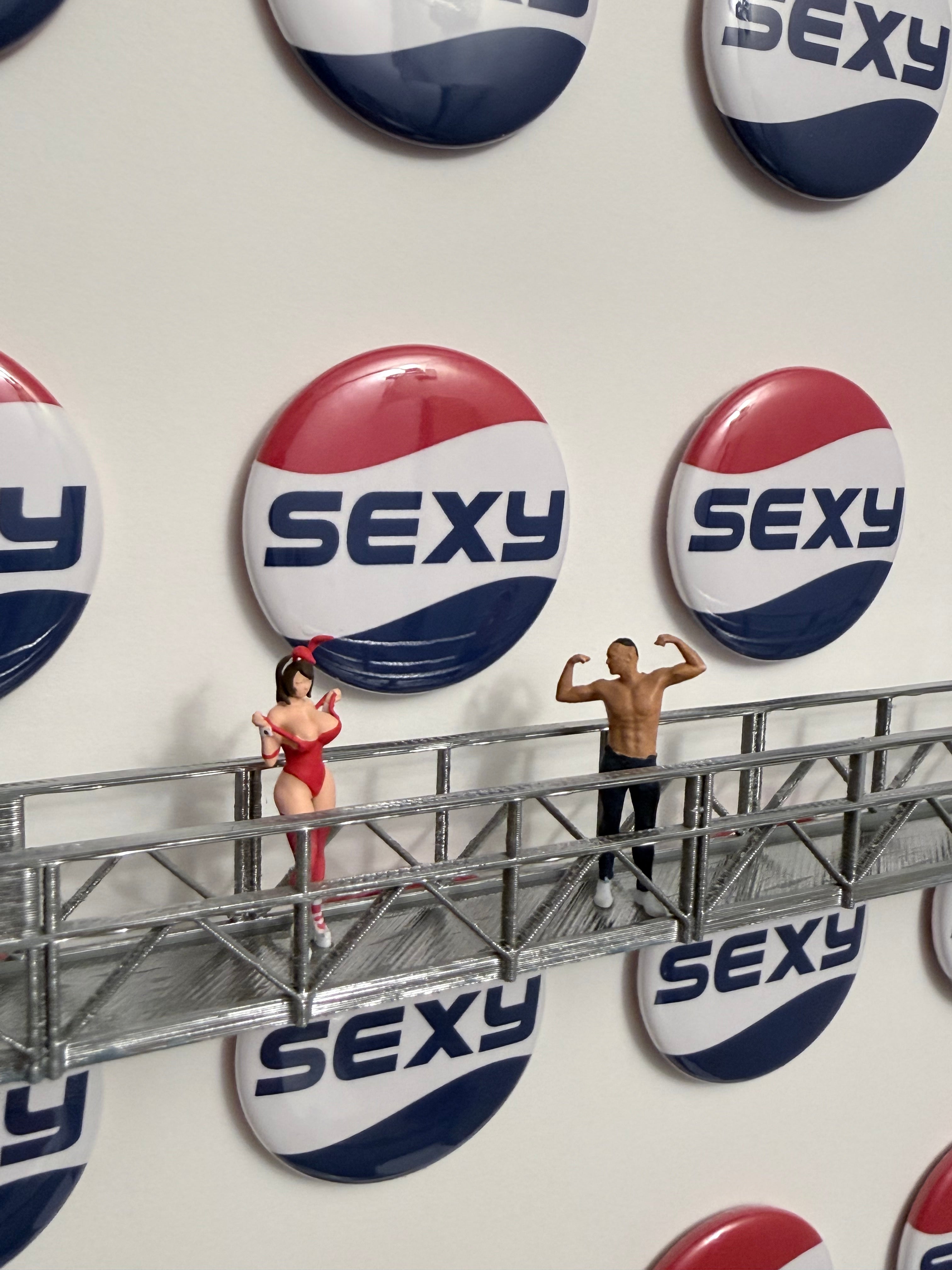 Button with 'SEXY' text on a white background with miniature figurines.