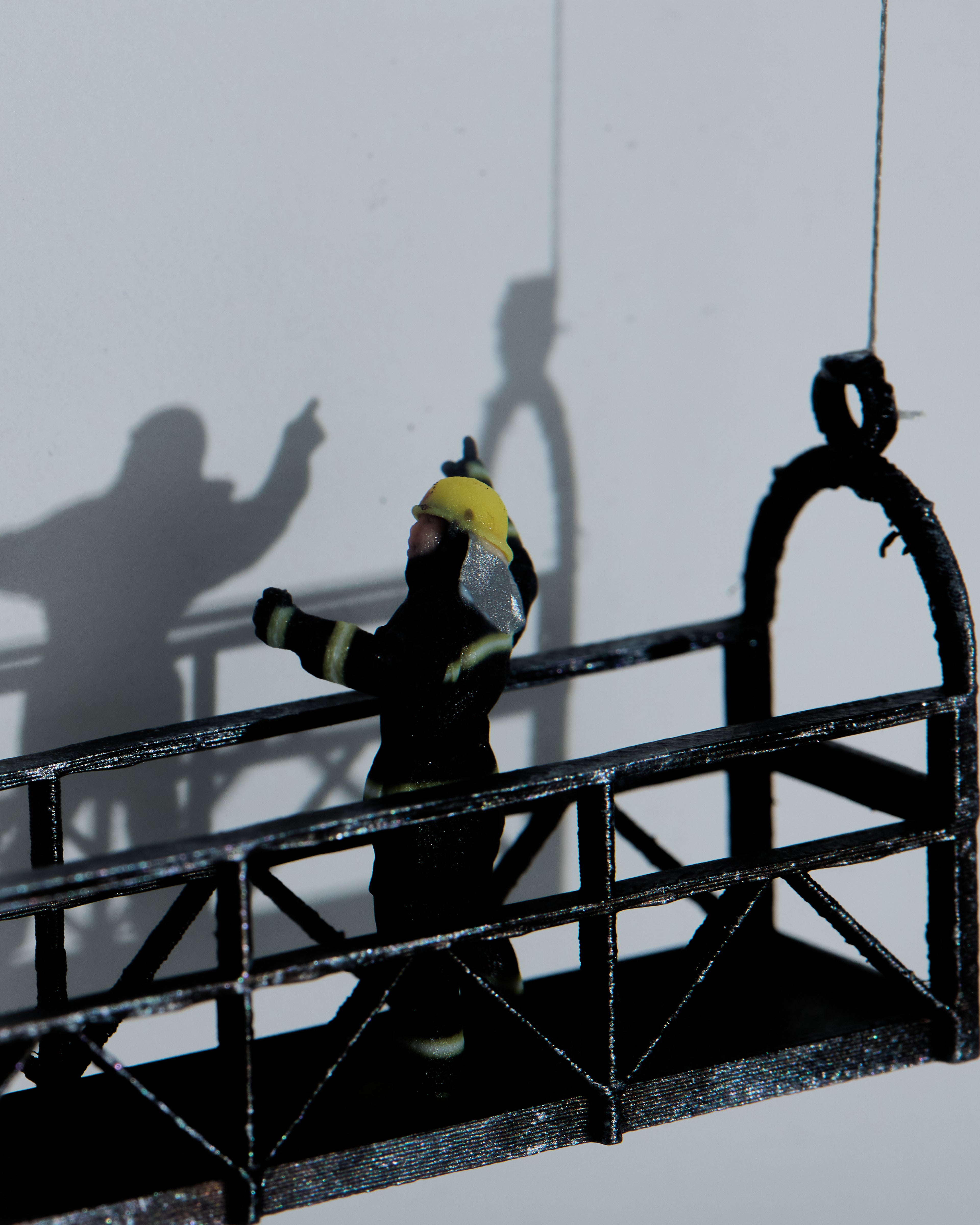 Miniature figurine with a yellow helmet on a small platform with a white background