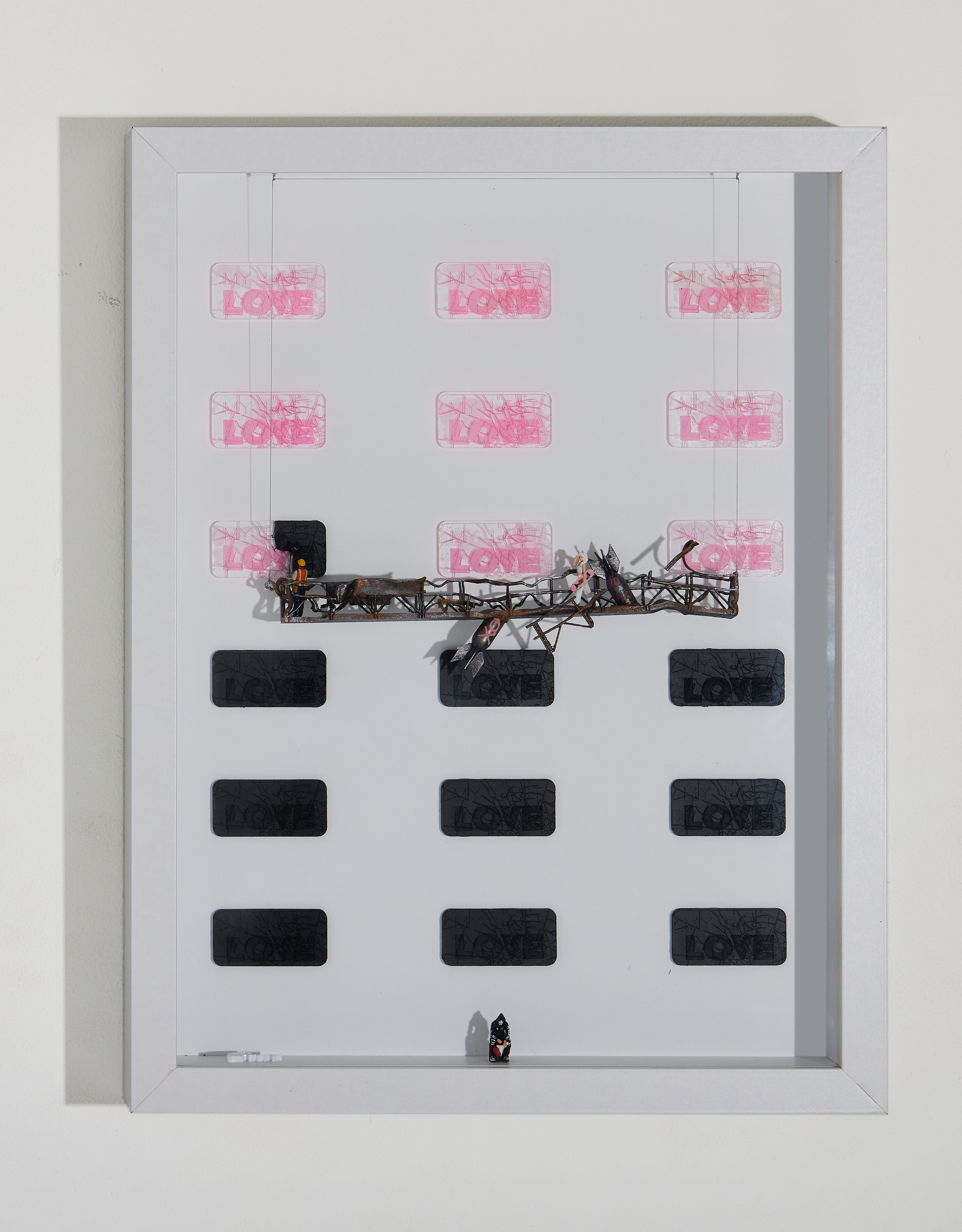 Shadow box artwork, repetitive text "my last love" across a white background. One miniature figurine covers the words with black paint. Another female miniature is walking on a destroyed platform. Last miniature is seating sad with flowers. 