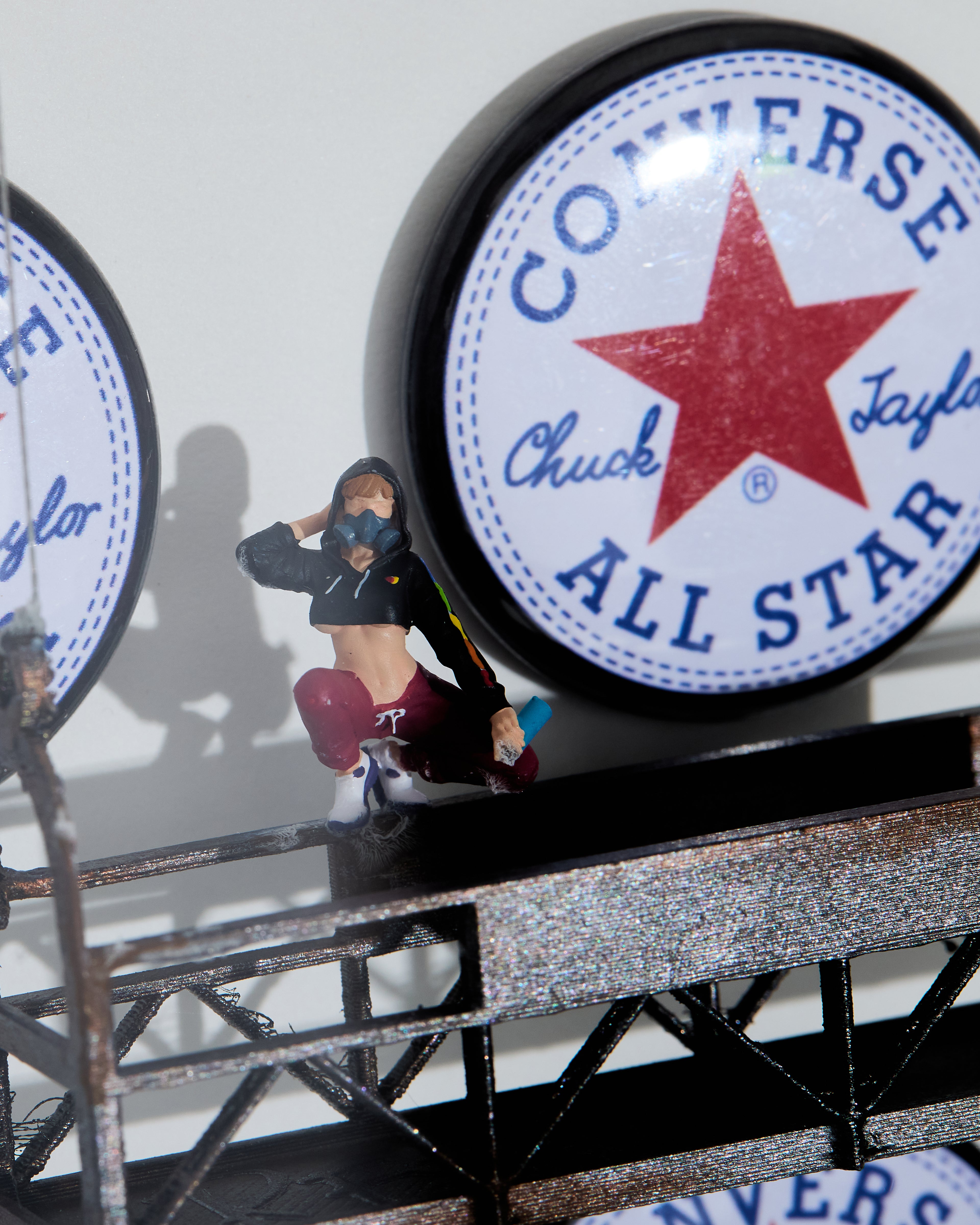 Shadow box Converse All Star logo with a miniature figurine on a platform with a spray can in her hand.