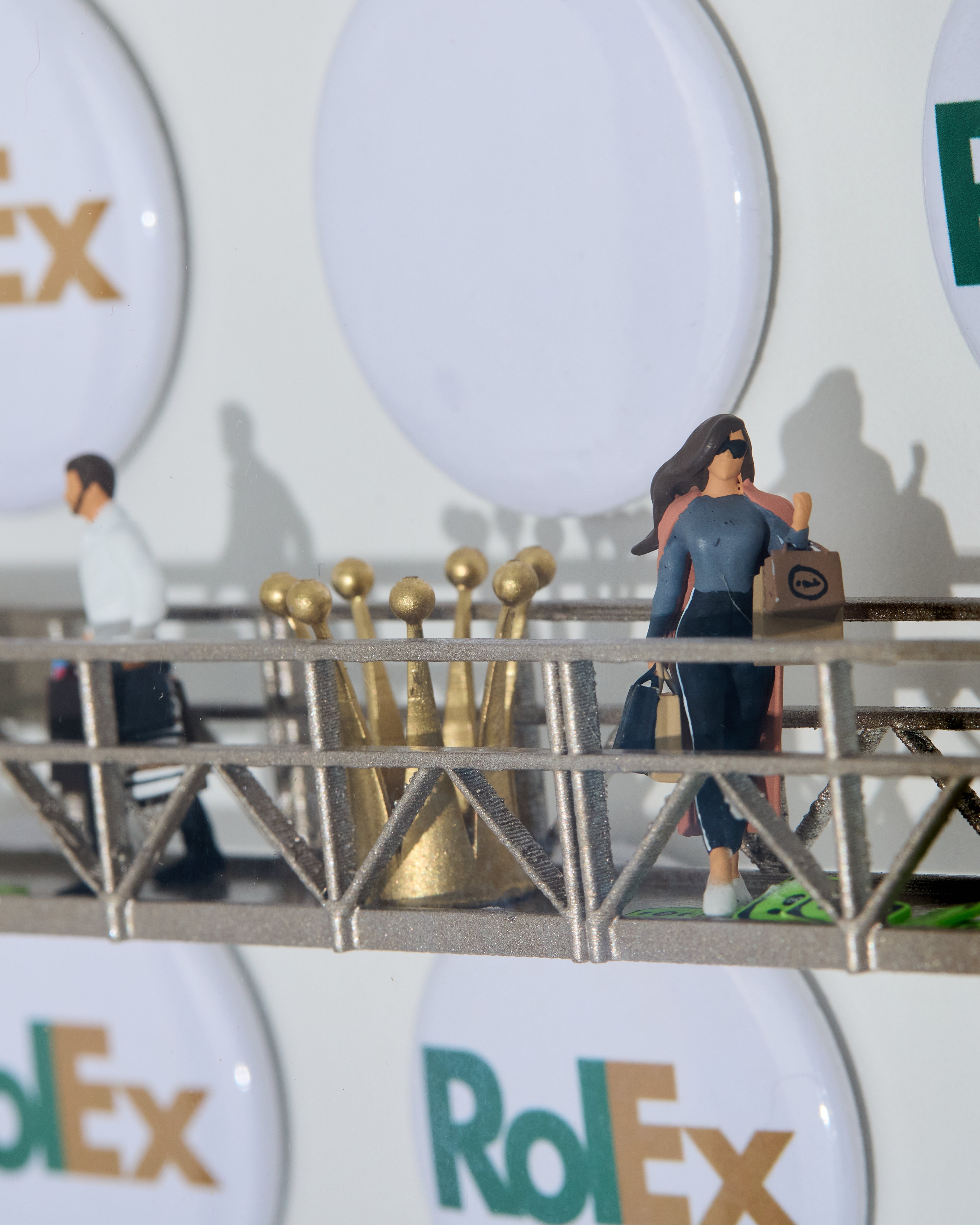 Model of a bridge with people and a crown in the background