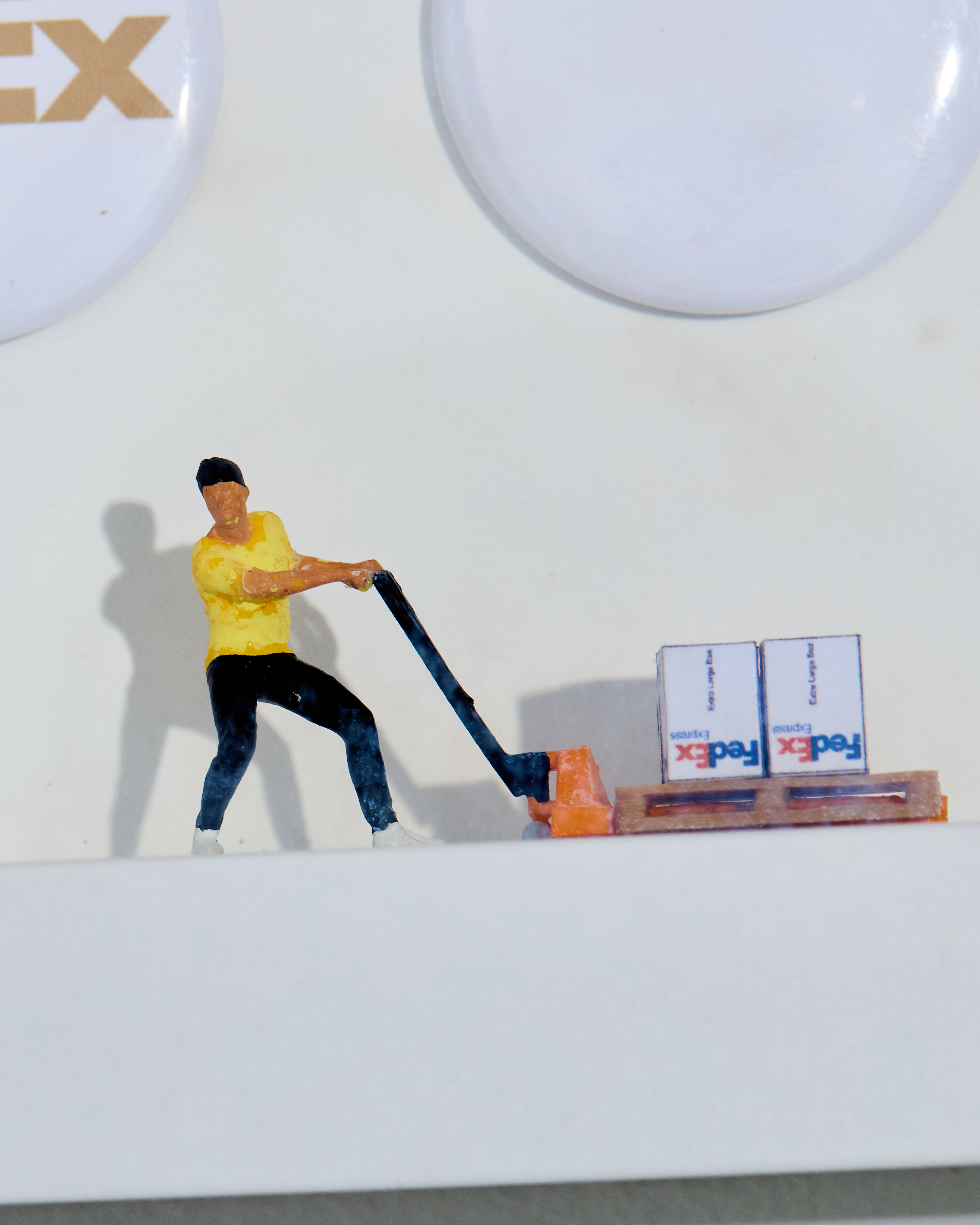 Model figure of a person with a trans pallet and boxes labeled 'FedEx' on a white background.