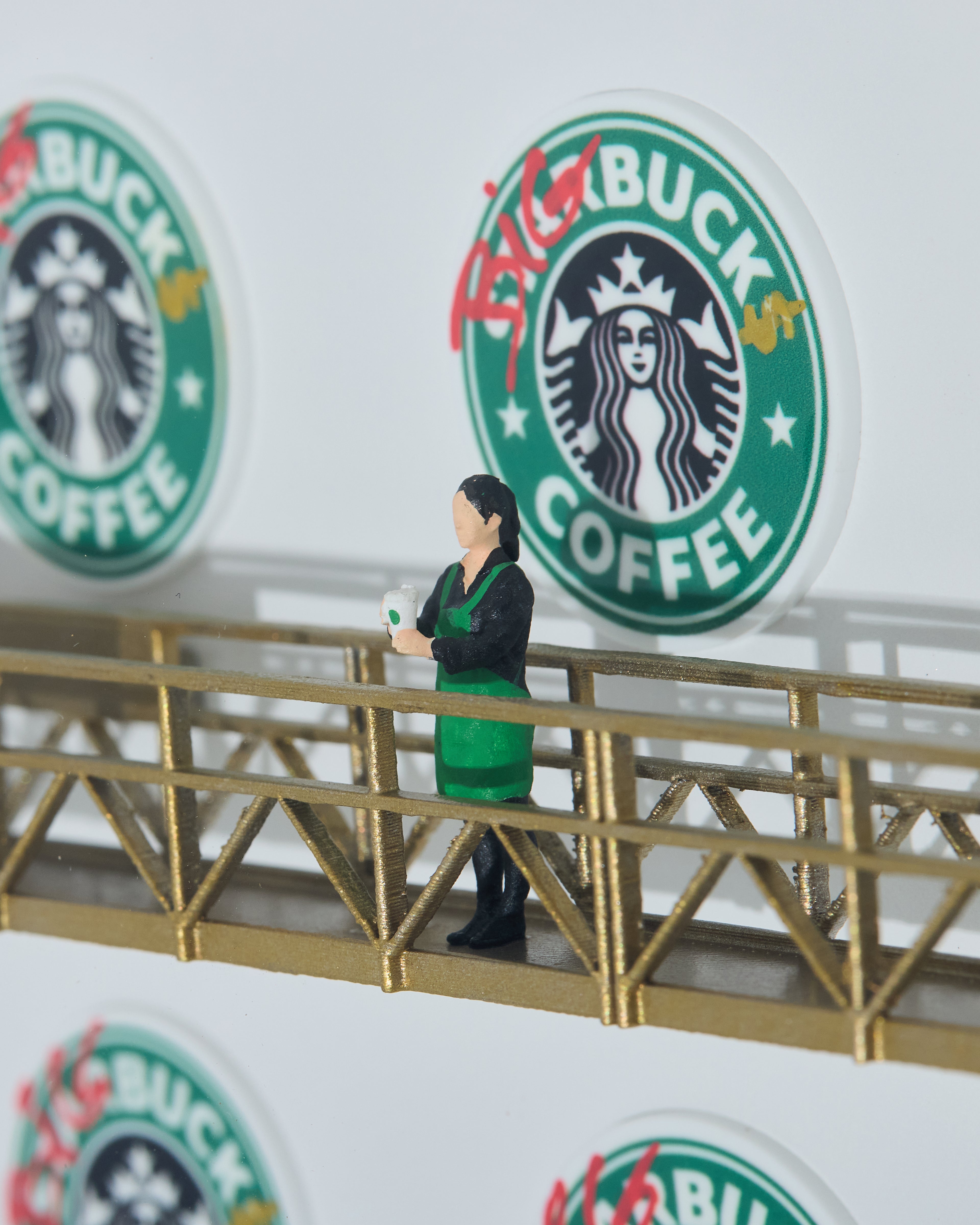 Miniature figurine in a green apron standing on a golden platform with Starbucks Coffee logos in the background, changed to BIG BUCKS